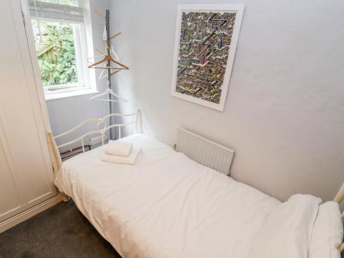 a small bedroom with a white bed and a window at Lime Cottage in Matlock