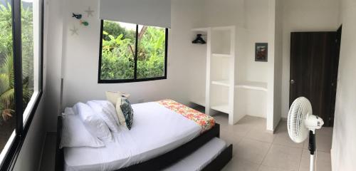 una camera da letto con un letto con lenzuola bianche e una finestra di Tu Paraíso en Santa Marta Casa con Piscina Privada Ideal para Grupos a Santa Marta