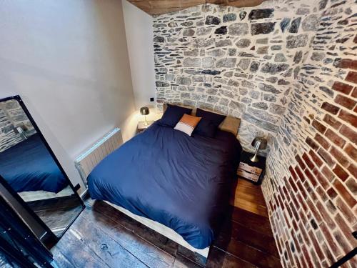 a bed in a room with a stone wall at Les Suites de la Tour d'Embas in Vitré