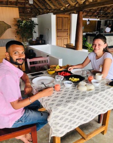 a man and woman sitting at a table with food at Vala House in Cherai Beach
