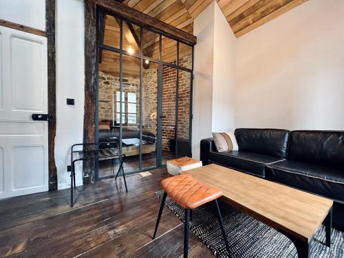 un salon avec un canapé noir et une table dans l'établissement Les Suites de la Tour d'Embas, à Vitré