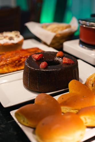 a chocolate cake with strawberries on a table with bread at Hotel Palmeiras in Santana do Livramento