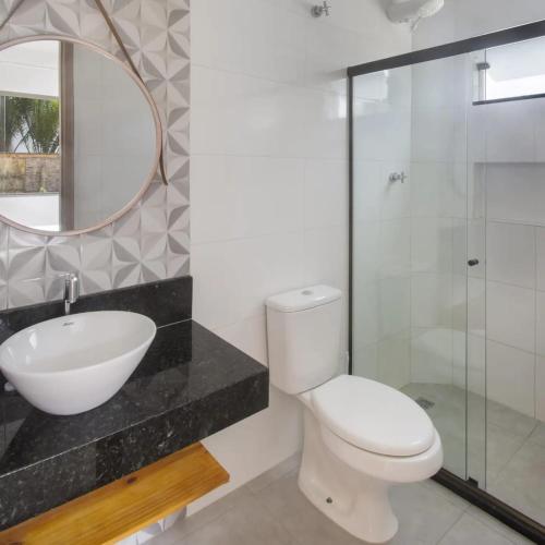 a bathroom with a toilet and a sink and a mirror at Camboa Village in Barra Grande