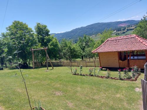 a cabin in a yard with flowers in a yard at Seosko domaćinstvo Alababa in Kosjerić
