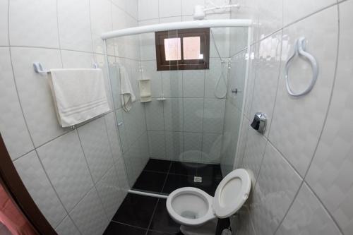 a white bathroom with a toilet and a shower at Ferrugem Pousada Região in Garopaba