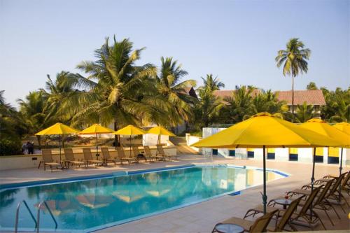 a swimming pool with yellow umbrellas and tables and chairs at Calangute Residency in Calangute