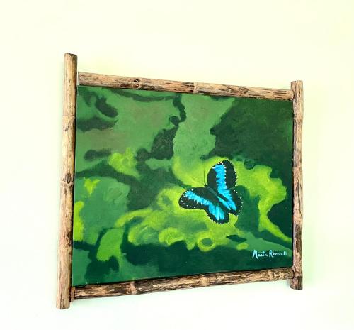 a painting of a blue butterfly in a wooden frame at Rinconcito Verde in Ujarrás