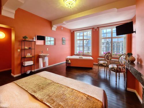 a bedroom with orange walls and a bed and a sink at Hotel Restaurant Steenhuyse in Oudenaarde