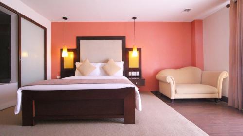a bedroom with a large bed and a chair at Coron Gateway Hotel & Suites in Coron