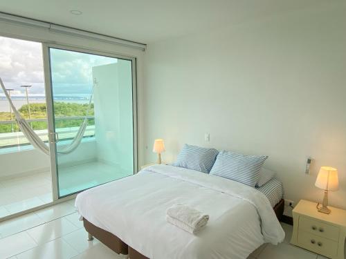 a white bedroom with a bed and a large window at Apartamento Cartagena en Morros frente a la playa in Cartagena de Indias