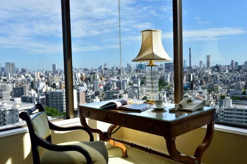 a desk with a lamp in front of a window at Hotel Chinzanso Tokyo in Tokyo