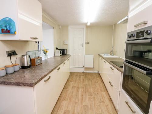 a kitchen with white cabinets and a wooden floor at Drake's Retreat in Plymouth