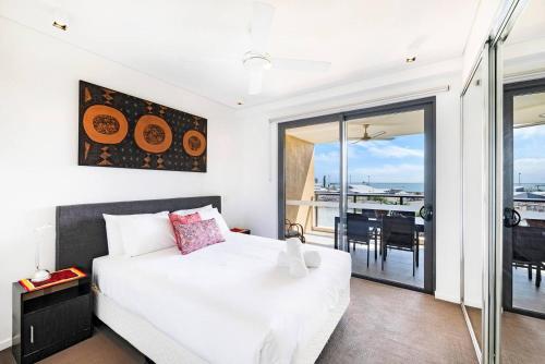 a bedroom with a bed and a balcony with a table at Darwin Waterfront Lagoon Hideaway with Sea Views in Darwin