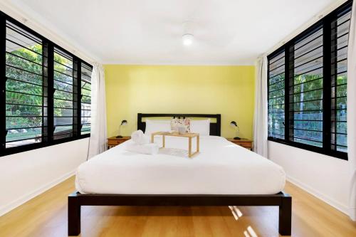 a bedroom with a white bed and large windows at Tropical Tranquillity - Spacious Poolside Cottage in Darwin