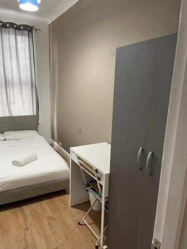 ロンドンにある03 Bedroom Apartment-Self Check inのベッドとデスクが備わる小さな客室です。