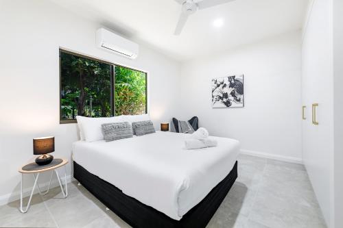 a white bedroom with a large white bed and a window at 'The White Belle' Poolside Paradise at Fannie Bay in Fannie Bay
