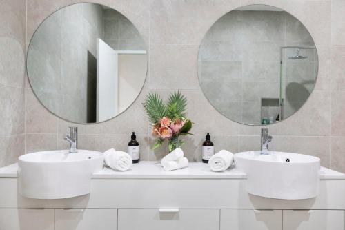 een badkamer met 2 wastafels en een grote spiegel bij 'The White Belle' Poolside Paradise at Fannie Bay in Fannie Bay