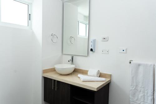 a white bathroom with a sink and a mirror at Hotel Qatar Cali in Cali
