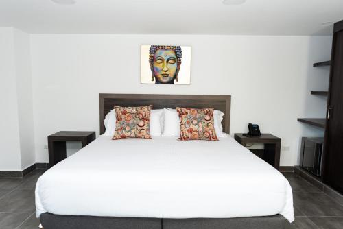 una camera da letto con un grande letto bianco con due tavoli di Hotel Qatar Cali a Cali