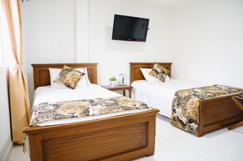 a bedroom with two beds and a tv on the wall at EL BORSALINO - Apartamento en Amazonas, Leticia in Leticia