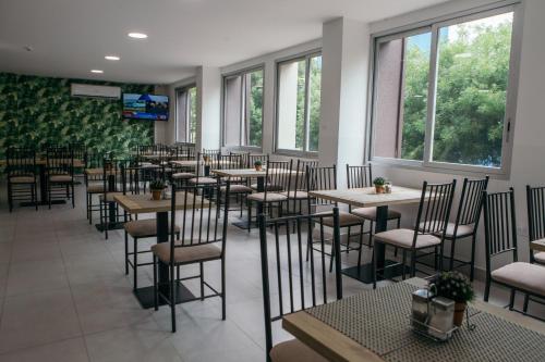 un comedor con mesas, sillas y ventanas en The Park Hotel, en Guayaquil