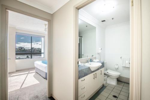 a white bathroom with a sink and a toilet at Bridgewater Apartments in Brisbane