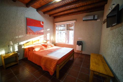 Un dormitorio con una cama grande y una ventana en Cabañas Parque Vistalba en Luján de Cuyo