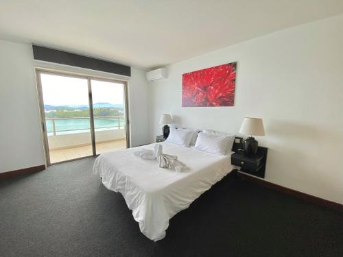 a bedroom with a large white bed with a large window at Casa Del Sole Apartments in Noumea