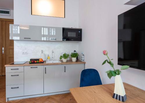 a kitchen with white cabinets and a table and a tv at PROVENIR HOME KWIATOWA 5 in Poznań