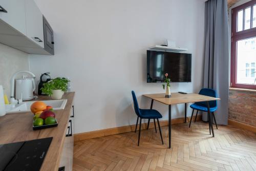 a kitchen with a table and chairs and a tv on the wall at PROVENIR HOME KWIATOWA 5 in Poznań