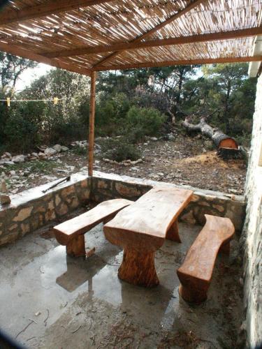 two wooden benches sitting under a wooden umbrella at Apartments by the sea Pomena, Mljet - 614 in Pomena