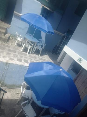 two blue umbrellas and chairs and a table and chairs at Hotel tanta Wasi in Quito