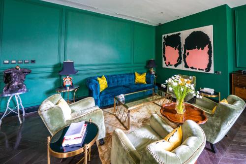 Gracie Art Hotel في بكين: غرفة معيشة بجدران خضراء وأريكة زرقاء