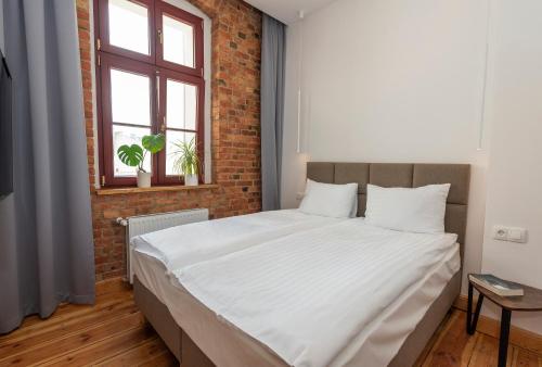a bedroom with a large bed with a brick wall at PROVENIR HOME KWIATOWA 5 in Poznań