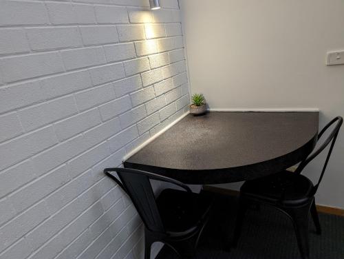 a black table with two chairs and a plant on it at Elm Court Motel in Albury