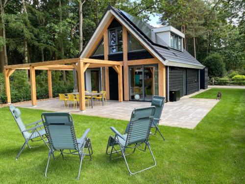 a group of chairs sitting on the grass in front of a house at Holiday Home in Lochem with Garden View in Lochem