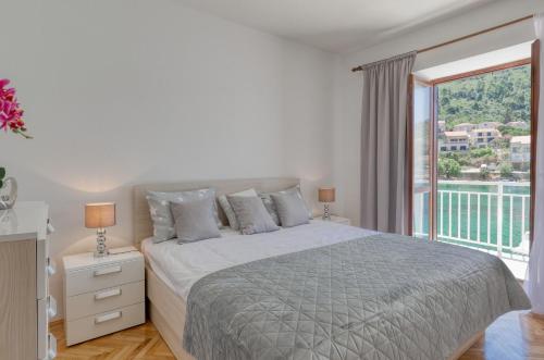 a white bedroom with a bed and a balcony at Apartments by the sea Brna, Korcula - 561 in Smokvica