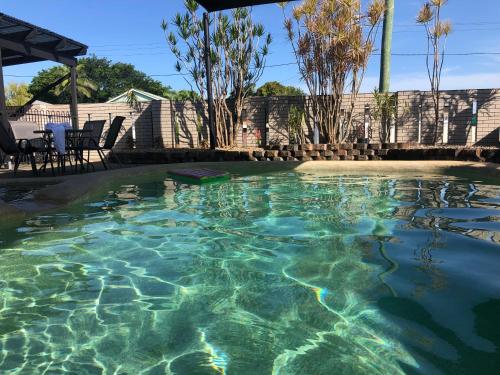 a swimming pool with clear water in a yard at Mackay Motor Inn in Mackay