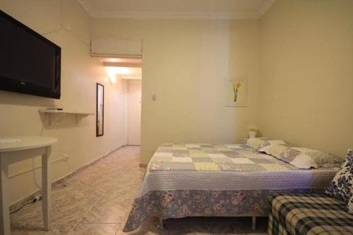 ein Schlafzimmer mit einem Bett, einem TV und einem Sofa in der Unterkunft Apartamento Copacabana 229 in Rio de Janeiro