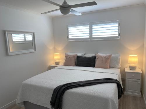 a bedroom with a large bed with two windows at Rainbow Beach Dream Newly Renovated Stylish One Bedroom Apartment in Rainbow Beach