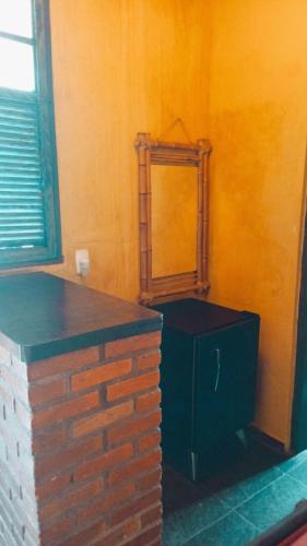 a bathroom with a mirror and a brick wall at Vila Santa Rosa Guest House in Ilhabela