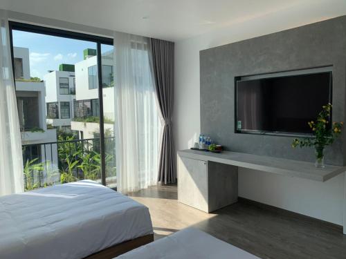 1 dormitorio con 1 cama y TV en la pared en Joy Villa Flamingo Đại Lải - 5 phòng ngủ, en Phúc Yên