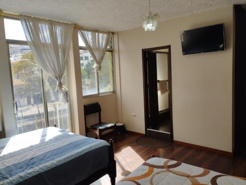 a bedroom with a bed and a tv and a window at HOTEL SARAGURO LOJA in Loja