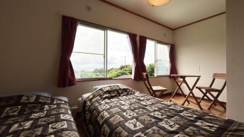 a bedroom with two beds and a window at 陽のあたる宿 サンセットパーム in Oshima