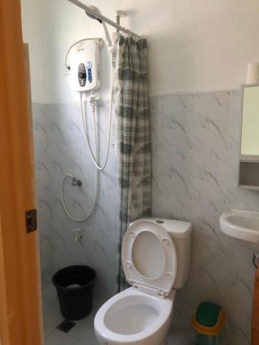 a bathroom with a shower and a toilet and a sink at MLB Beachfront Apartment in Siquijor