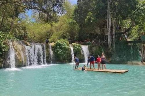 a group of people standing in the water near a waterfall at LightHaus DP Garden Resort in Siquijor