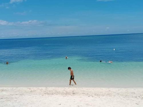 a man walking on a beach with people in the water at LightHaus DP Garden Resort in Siquijor