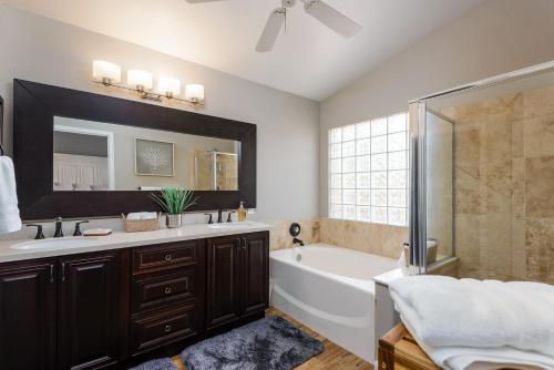 une salle de bain avec une baignoire, un lavabo et un miroir dans l'établissement Casa De Mojave home, à Scottsdale