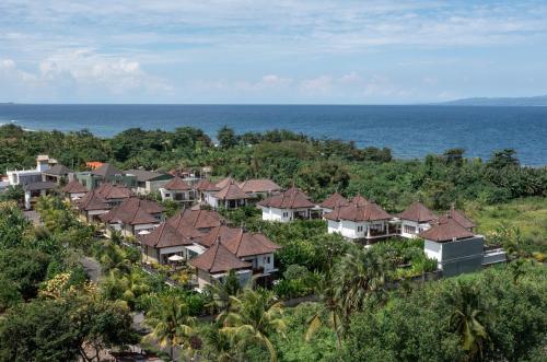 un groupe de maisons sur une colline à côté de l'océan dans l'établissement Desa Swan Villas & SPA, Keramas, à Keramas