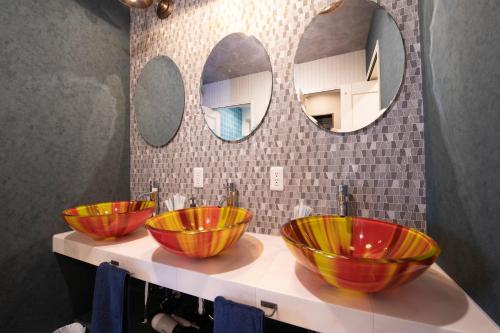 3 bols sur un comptoir dans une salle de bains avec 2 miroirs dans l'établissement THE BEEHIVE AIOI, à Otaru